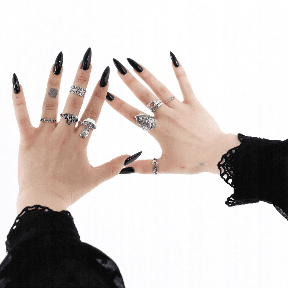 Two hands adorned with various silver rings and black nail polish against a white background.